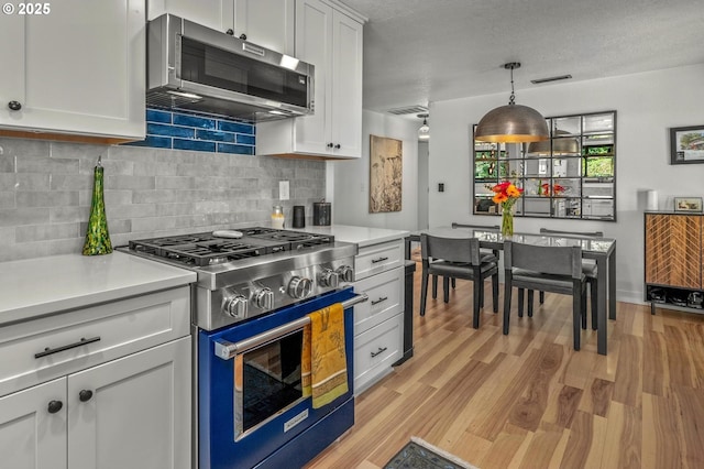 19919 SE Borges Rd, Damascus, OR 97089 - kitchen with stainless steel appliances, light countertops, backsplash, light wood-style flooring, and white cabinetry