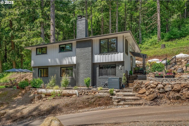 19919 SE Borges Rd, Damascus, OR 97089 - view of front facade featuring stairs, brick siding, a chimney, and a wooded view