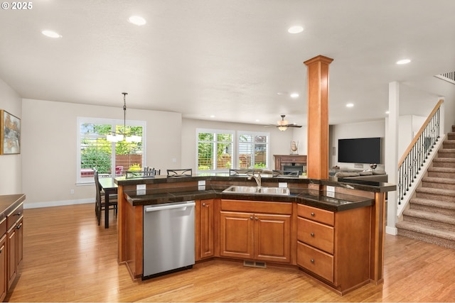 kitchen featuring a ceiling fan, stainless steel dishwasher, light wood-type flooring, a sink, and open floor plan