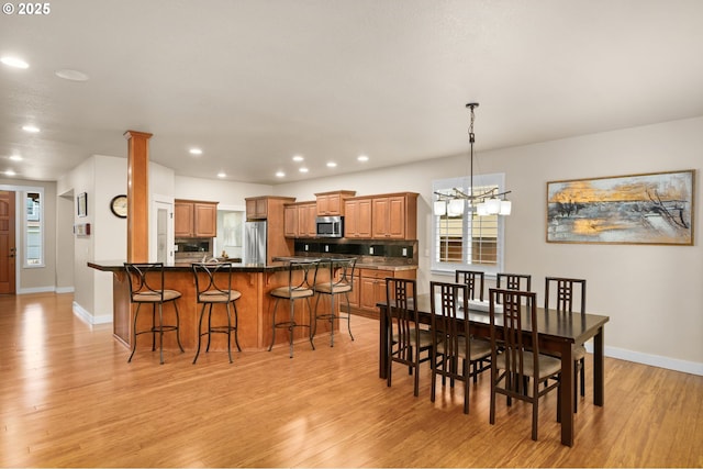 dining area with recessed lighting, baseboards, light wood finished floors, and a chandelier