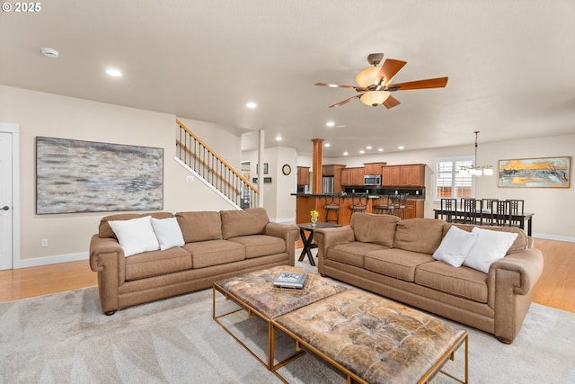 living area featuring baseboards, ceiling fan, stairway, light wood-type flooring, and recessed lighting