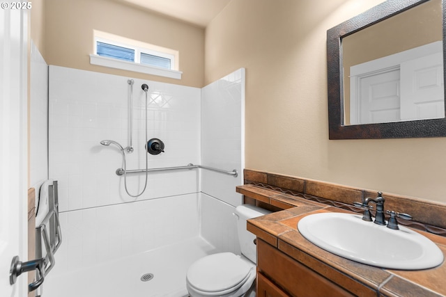 full bath with toilet, a tile shower, and vanity