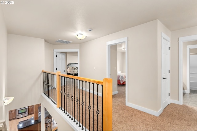 hallway featuring carpet floors, baseboards, an upstairs landing, and visible vents