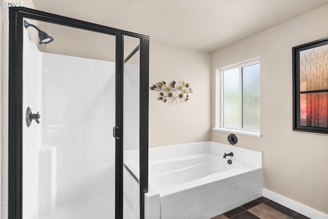 bathroom featuring baseboards, a bath, a stall shower, and tile patterned floors