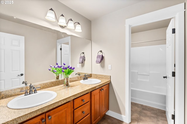 full bath featuring double vanity, a sink, baseboards, and tile patterned floors