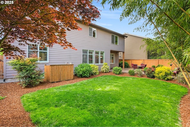 rear view of property with a yard, a patio, and fence