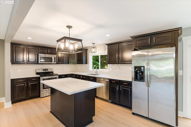2706 SE Spruce St, Hillsboro, OR 97123 - kitchen featuring stainless steel appliances, light wood-style flooring, a sink, hanging light fixtures, and tasteful backsplash
