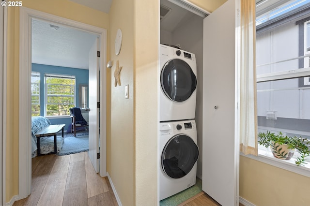 6708 N Pittsburg Ave, Portland, OR 97203 - washroom featuring stacked washer and clothes dryer, light wood-type flooring, and baseboards