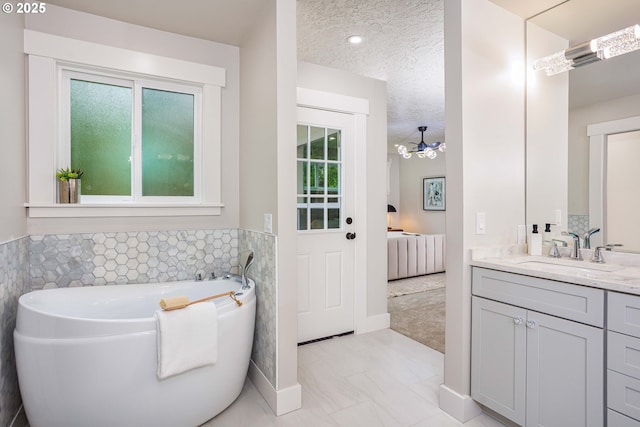 33500 E Bell Rd, Corbett, OR 97019 - bathroom featuring tile walls, marble finish floors, vanity, a tub to relax in, and a textured ceiling