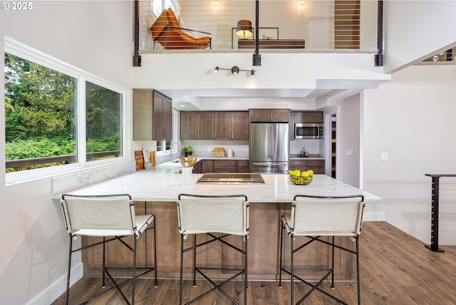 33500 E Bell Rd, Corbett, OR 97019 - kitchen with appliances with stainless steel finishes, a peninsula, wood finished floors, dark brown cabinets, and a towering ceiling