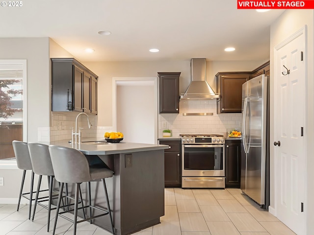 42019 NW Oak Way, Banks, OR 97106 - kitchen featuring wall chimney range hood, stainless steel appliances, a peninsula, decorative backsplash, and a kitchen breakfast bar