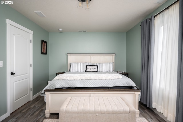 bedroom featuring visible vents, baseboards, and dark wood-style flooring