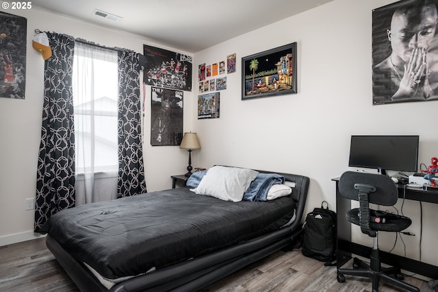 bedroom with wood finished floors, visible vents, and baseboards