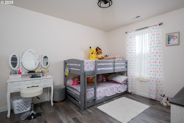 bedroom featuring wood finished floors, visible vents, and baseboards