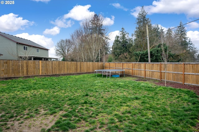 view of yard featuring a trampoline and a fenced backyard