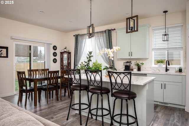 kitchen with dark wood finished floors, a healthy amount of sunlight, a center island, and a kitchen bar