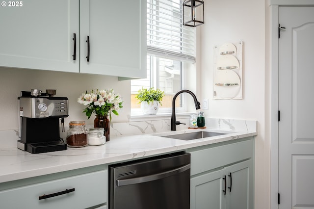 kitchen featuring dishwasher, light stone countertops, and a sink