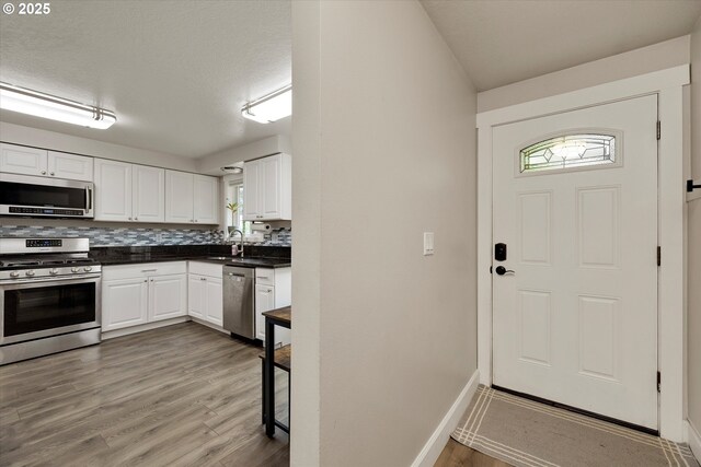 7353 SE Thiessen Rd, Milwaukie, OR 97267 - kitchen featuring stainless steel appliances, dark countertops, white cabinetry, and wood finished floors