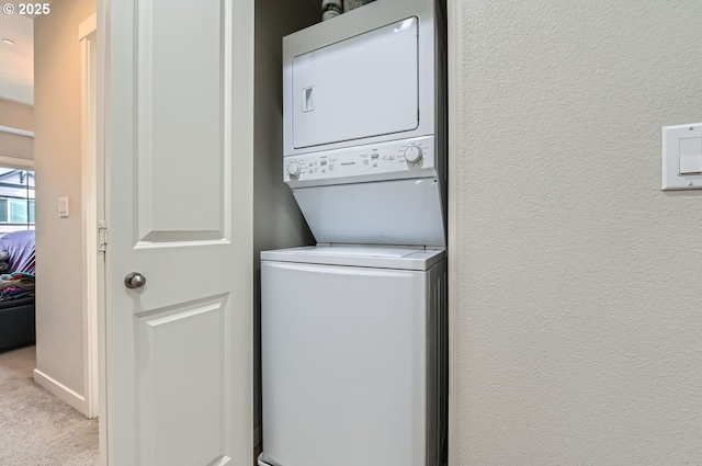 washroom featuring stacked washer and clothes dryer and light carpet