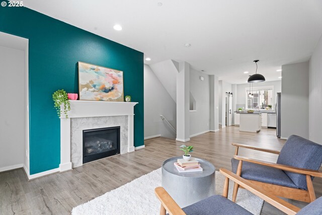 living area with recessed lighting, a premium fireplace, baseboards, and light wood finished floors