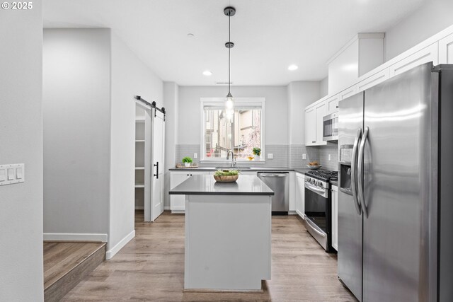 kitchen featuring dark countertops, open shelves, white cabinets, appliances with stainless steel finishes, and a barn door