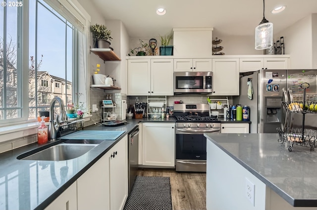 kitchen with hanging light fixtures, decorative backsplash, white cabinetry, appliances with stainless steel finishes, and sink