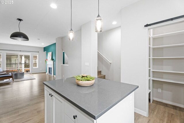 kitchen featuring decorative light fixtures, a kitchen island, white cabinetry, recessed lighting, and light wood finished floors