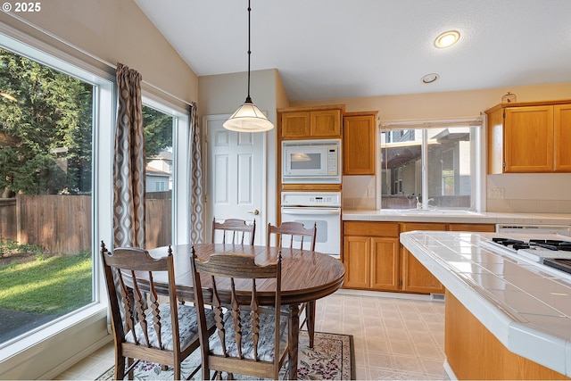 1545 NE Gertz Rd, Portland, OR 97211 - kitchen featuring white appliances, tile counters, a sink, vaulted ceiling, and pendant lighting
