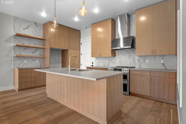 kitchen with decorative backsplash, range with two ovens, a kitchen island with sink, and wall chimney range hood