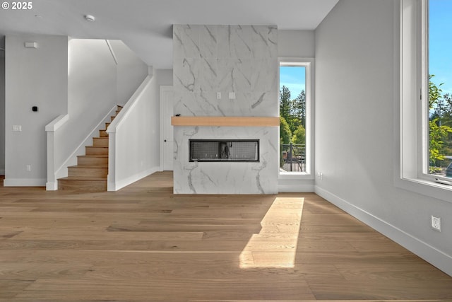 unfurnished living room featuring a wealth of natural light, a high end fireplace, and light wood-type flooring