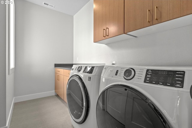 laundry room featuring separate washer and dryer and cabinets