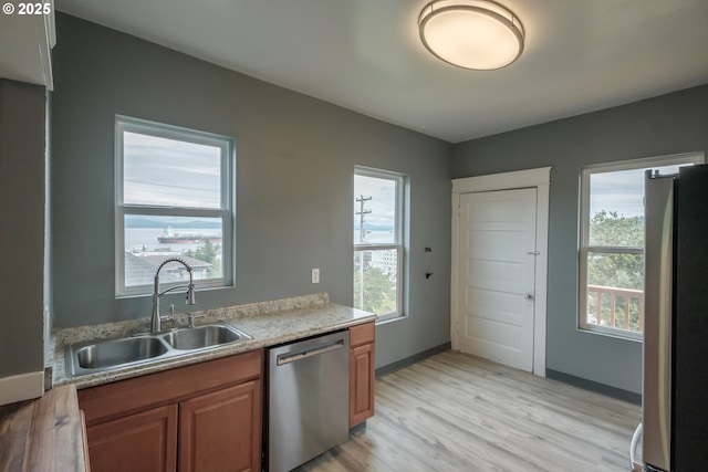 640 8th St, Astoria, OR 97103 - kitchen with brown cabinets, a sink, stainless steel appliances, a wealth of natural light, and light wood-style floors
