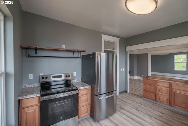 640 8th St, Astoria, OR 97103 - kitchen featuring light wood-style floors, open shelves, light stone counters, and appliances with stainless steel finishes