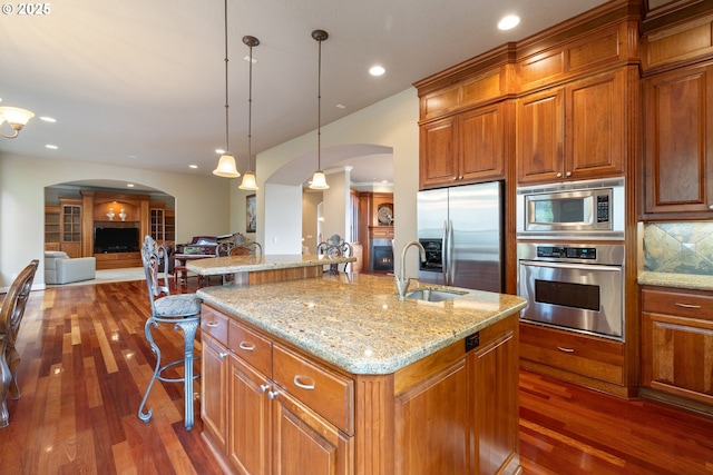 14079 SE Alta Vista Dr, Happy Valley, OR 97086 - kitchen with brown cabinets, dark wood finished floors, stainless steel appliances, arched walkways, and a sink