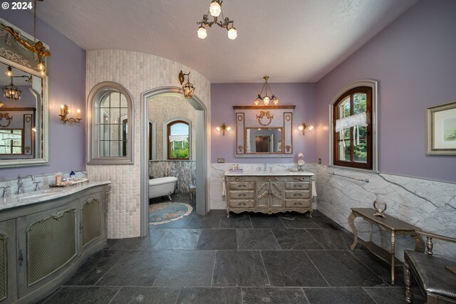 26480 SW Wilken Ln, West Linn, OR 97068 - full bathroom featuring tile walls, healthy amount of natural light, two vanities, stone tile floors, and a soaking tub