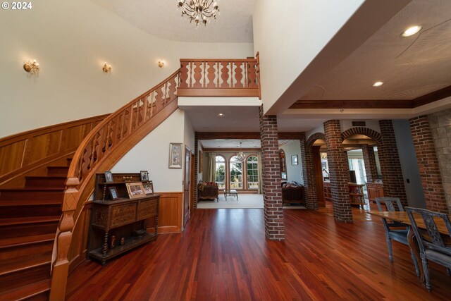 26480 SW Wilken Ln, West Linn, OR 97068 - entrance foyer with decorative columns, a chandelier, wood finished floors, a wainscoted wall, and stairway