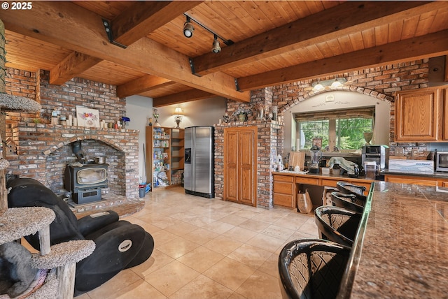 interior space featuring beamed ceiling, rail lighting, a wood stove, and wood ceiling