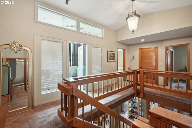 corridor featuring high vaulted ceiling, dark carpet, and plenty of natural light