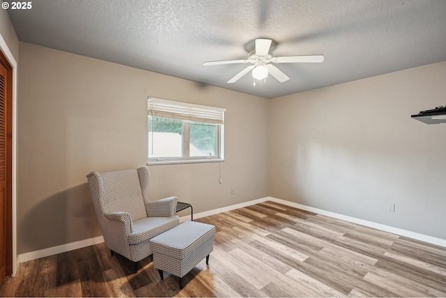 sitting room featuring ceiling fan, a textured ceiling, and light wood-type flooring