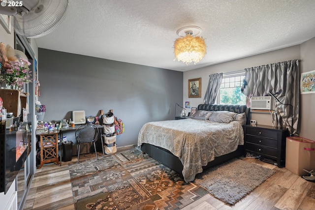 bedroom with wood-type flooring, a textured ceiling, and cooling unit