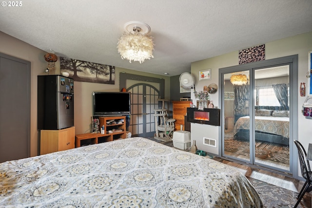 bedroom with hardwood / wood-style floors, a textured ceiling, and a notable chandelier