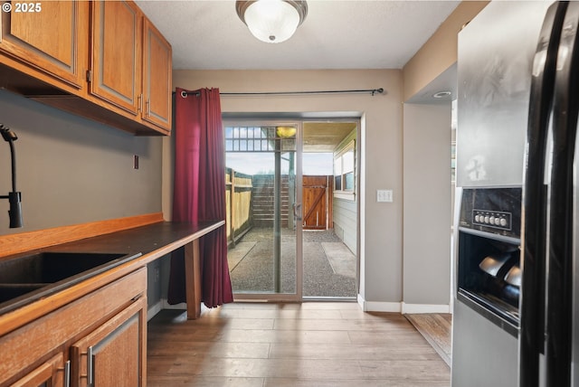 kitchen featuring sink, stainless steel refrigerator with ice dispenser, and light hardwood / wood-style flooring