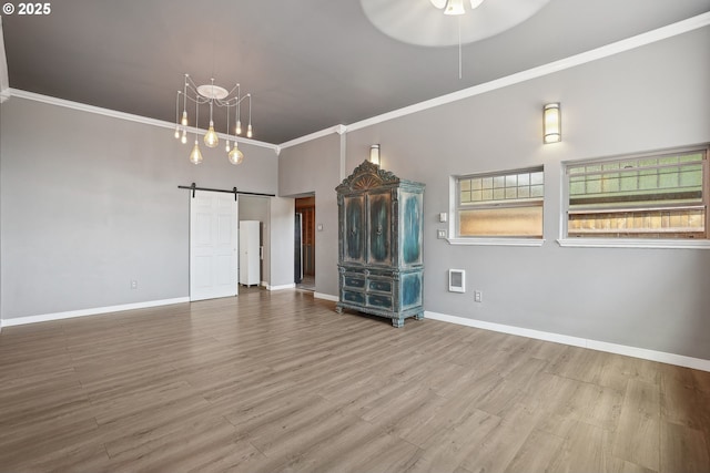 unfurnished room featuring a barn door, crown molding, wood-type flooring, and a high ceiling