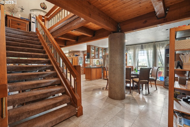 stairway with decorative columns, tile patterned flooring, beamed ceiling, and wood ceiling