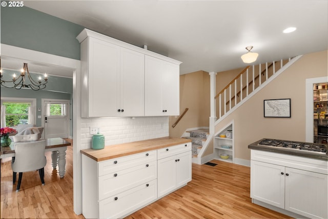 224 NE 44th Ave, Portland, OR 97213 - kitchen featuring butcher block countertops, gas stovetop, light wood-style floors, white cabinetry, and a chandelier