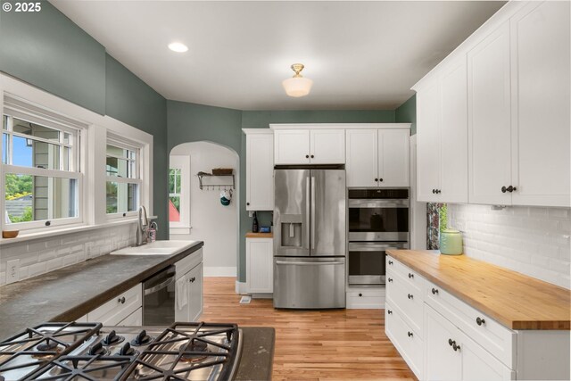 224 NE 44th Ave, Portland, OR 97213 - kitchen with stainless steel appliances, wood counters, a sink, tasteful backsplash, and arched walkways
