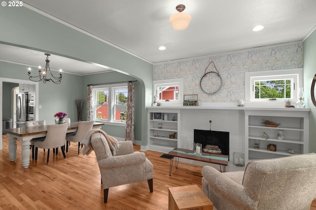 224 NE 44th Ave, Portland, OR 97213 - living room with ornamental molding, a brick fireplace, light wood-type flooring, plenty of natural light, and a chandelier
