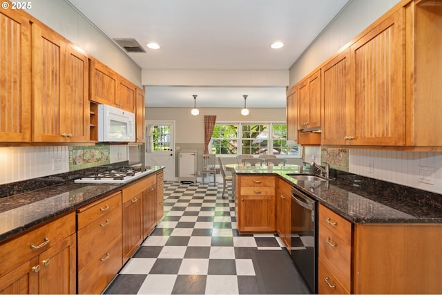 kitchen featuring white appliances, visible vents, a sink, brown cabinets, and dark floors