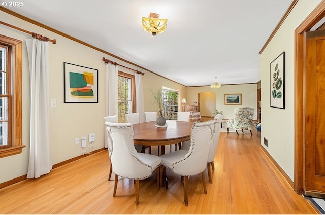 dining room with crown molding, baseboards, and light wood-style floors