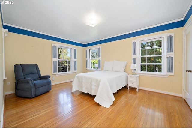 bedroom with multiple windows, light wood-style flooring, and baseboards